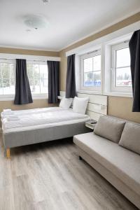 a room with two beds and a couch and windows at Storebaug Motell in Moss