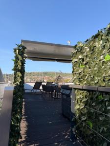 a deck with a green wall with tables and chairs at JungleHouse - Floating House in Portorož +1 photo