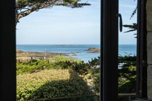 a view of the ocean from a door at LA PINÈDE - Villa 4 étoiles vue mer - Plage à 30 m - Emplacement exceptionnel in Dinard
