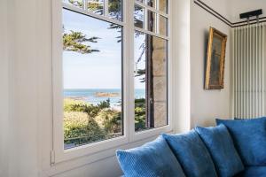a living room with a large window looking out at the ocean at LA PINÈDE - Villa 4 étoiles vue mer - Plage à 30 m - Emplacement exceptionnel in Dinard