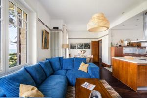 a blue couch in a living room with a kitchen at LA PINÈDE - Villa 4 étoiles vue mer - Plage à 30 m - Emplacement exceptionnel in Dinard