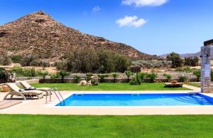 a pool in a yard with a mountain in the background at Muses Beach Villas - Urania in Sitia +9 photos