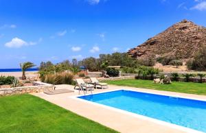 a swimming pool in a yard with a mountain in the background at Muses Beach Villas - Urania in Sitia