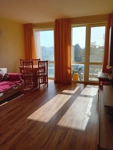 a living room with a table and chairs and large windows at Студио Ахелой in Aheloy