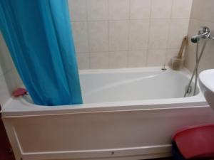 a bathroom with a tub with a blue shower curtain at Студио Ахелой in Aheloy +2 photos