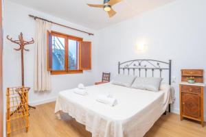 a bedroom with a bed with white sheets and a window at Can Pons in Can Picafort