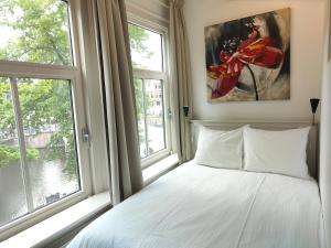 a bedroom with a bed and two windows at The Blue Stairs in Amsterdam
