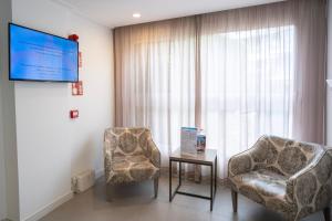 Ein Zimmer mit zwei Stühlen, einem Fernseher und einem Tisch in der Unterkunft BLUESEA Cala Millor in Cala Millor + 33 Fotos