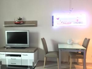 ein Wohnzimmer mit einem TV und einem Tisch mit Stühlen in der Unterkunft Apartment Warnemünde 16 in Warnemünde