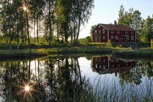 a house sitting next to a body of water with a barn at Pensionat Sågknorren in Bygget