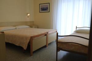 ein Schlafzimmer mit zwei Betten, einem Tisch und einem Fenster in der Unterkunft Hotel Soave in Cervia + 29 Fotos