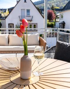 a vase of flowers and a glass of wine on a table at Ferienwohnungen Moselpanorama und Moselblick in Bullay