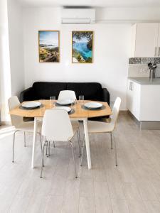 a dining room with a wooden table and white chairs at Cala Porter Soleil & Mer Collection in Cala en Porter +33 photos