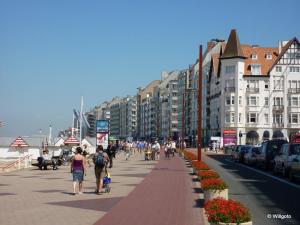 eine Gruppe von Menschen, die einen Bürgersteig neben Gebäuden entlang gehen in der Unterkunft Merida in Knokke-Heist