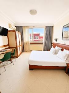 a hotel room with a bed and a table and a desk at Hôtel Shalimar in Antananarivo