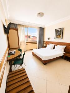 a hotel room with a bed and a desk and a window at Hôtel Shalimar in Antananarivo