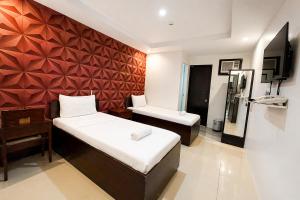 a hotel room with two beds and a mirror at Obrero Suites Davao in Davao City +19 photos