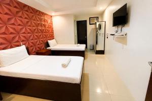 a hotel room with two beds and a tv at Obrero Suites Davao in Davao City