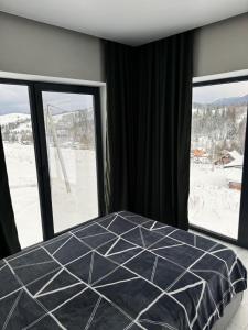a bedroom with a bed and two large windows at SoTA SKI in Pilipets