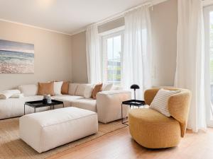 a living room with a white couch and chairs at Seebär in Scharbeutz +42 photos