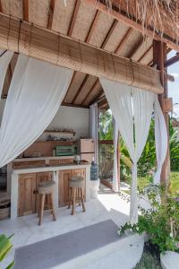 an outdoor kitchen with a table and stools under a roof at Villa Nyantara - Private tropical villa in Gili Islands