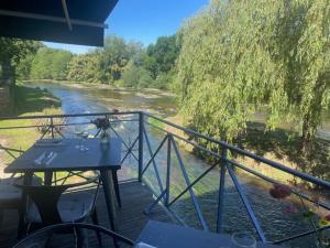 a balcony with a table with a view of a river at Hostellerie Les Griffons in Brantome en Perigord