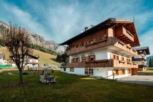 a house in a field next to a mountain at Appartamenti Kratter Pietro in Sappada