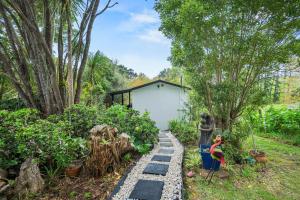 a garden with a path with a house in the background at Country Nirvana in Pataua