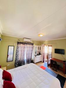 a bedroom with a large white bed and a kitchen at Clock Inn Self Catering Accommodation in Gaborone