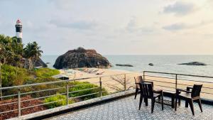 two chairs and a table next to a beach with a lighthouse at Eevara Beach By Shore in Kaup