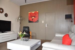 a living room with a white couch and a tv at Het Voorhuis in Grolloo
