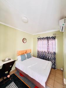 a bedroom with a bed and a desk and a window at Clock Inn Self Catering Accommodation in Gaborone +2 photos
