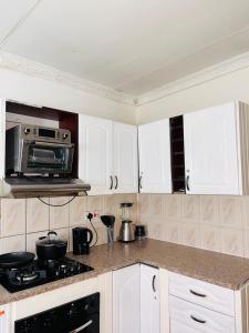 a kitchen with white cabinets and a microwave at Clock Inn Self Catering Accommodation in Gaborone