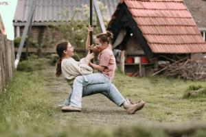 two girls are sitting on a swing with an umbrella at Hoeve de Betuwe by Feather Down in Dreumel
