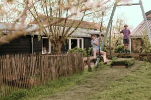 two children on a swing in front of a house at Hoeve de Betuwe by Feather Down in Dreumel +19 photos