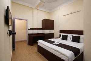a hotel room with a bed and a television at Whitestone Inn in Guwahati +7 photos