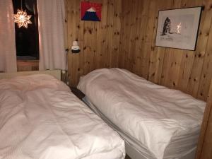 a bedroom with two beds in a wooden wall at Grímsstaðir Guesthouse in Grímsstaðir á Fjöllum