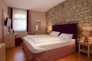 a bedroom with a large bed and a stone wall at Hotel Am Turm in Kaufbeuren
