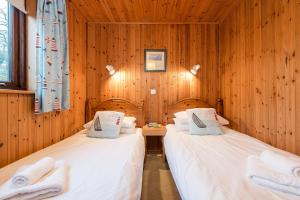 two beds in a room with wooden walls at E29 -Lawnside in Truro
