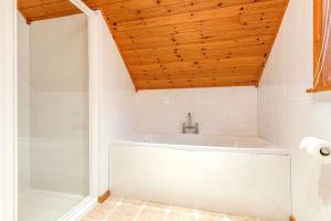a white tub in a bathroom with a wooden ceiling at E29 -Lawnside in Truro