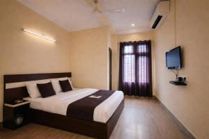 a hotel room with a bed and a television at Whitestone Inn in Guwahati