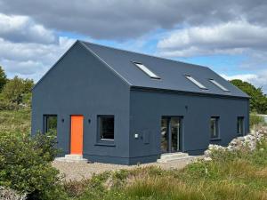 a blue house with an orange door in a field at Cottage 505 - Roundstone in Roundstone