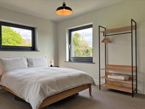 a bedroom with a large bed and two windows at Cottage 505 - Roundstone in Roundstone