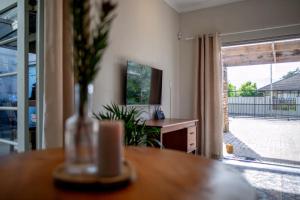 a living room with a table with a vase of flowers at Eunoia Cottage in Paarl