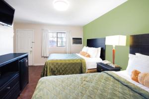 a hotel room with two beds and a television at Executive Inn & Kitchenette Suites-Eagle Pass in Eagle Pass