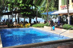 un hombre está de pie junto a una piscina en Hotel El Velero, en Playa Hermosa