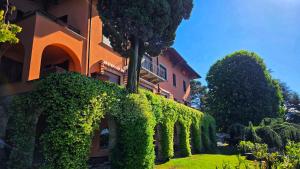a building covered in green ivy next to a yard at Villa Belora in Gera Lario