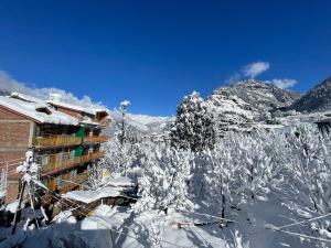 a building covered in snow next to a mountain at Monkeys Junction in Manāli +14 photos