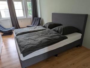 a bed with a gray comforter and two chairs at Ferienwohnung Altstadt Lemgo in Lemgo