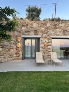 a patio with two chairs and a stone wall at On The Rocks - The Pebbles - Serviced Villas in Ios Chora